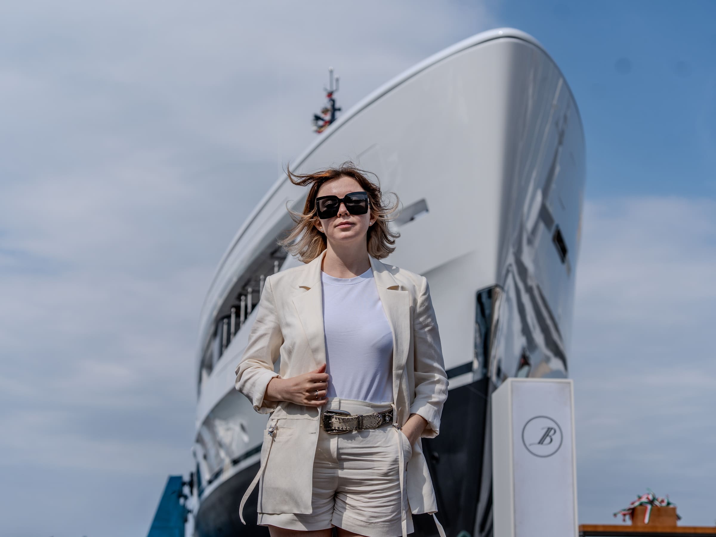 Yauheniya Kuzmitch walking past the bow of a superyacht at a shipyard