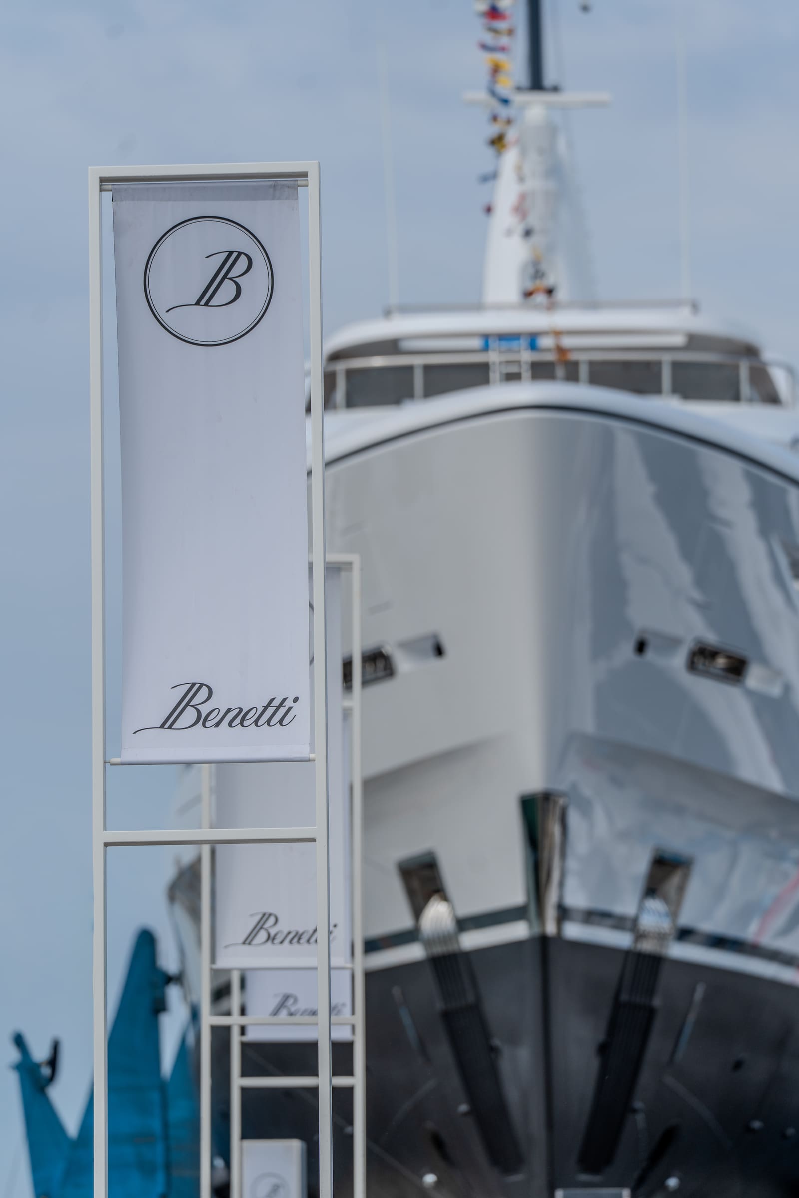 A Benetti flag flying beside a superyacht bow at the shipyard